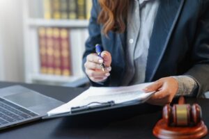 Female lawyer working on contract papers in a law firm office, focused on the pen.